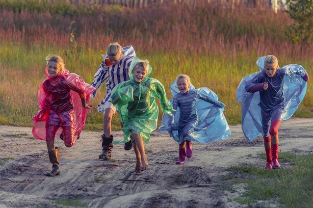 people in green and blue jacket walking on dirt road during daytime
