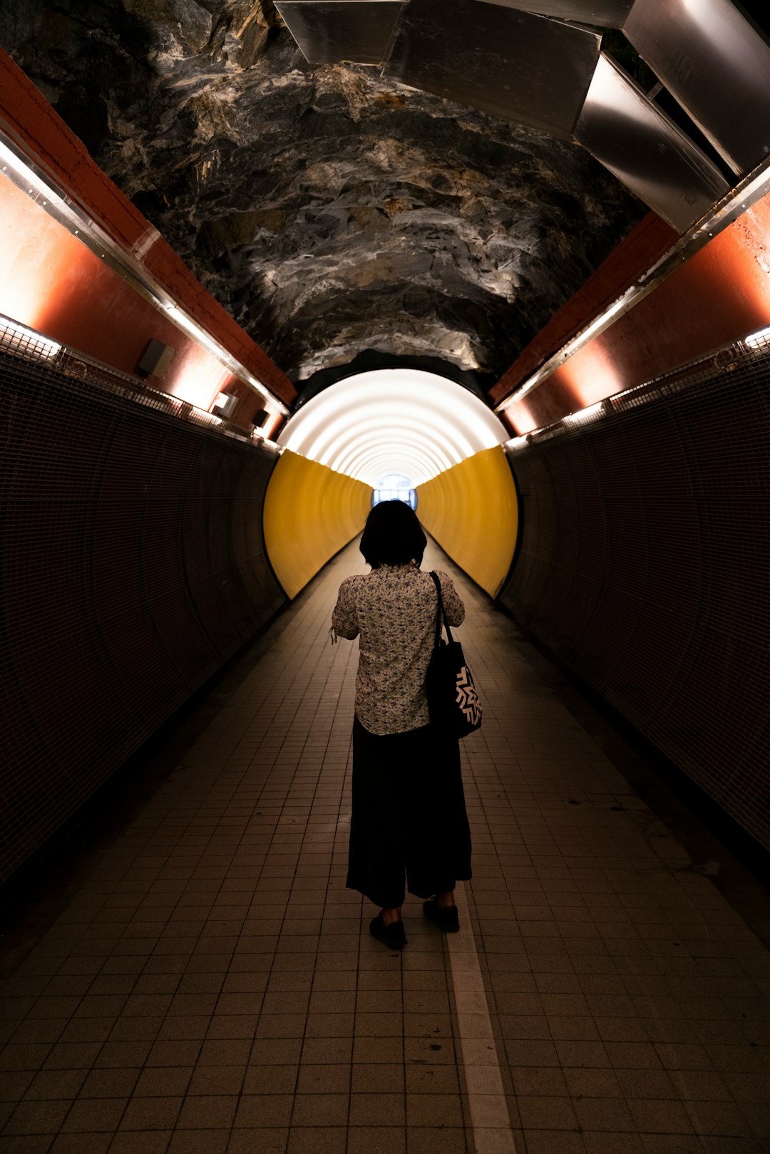 woman in black and white coat standing on tunnel