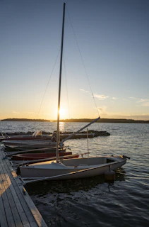 A classic 40ft sailboat gently moored by a rustic dock at sunset on Lake of the Ozarks.