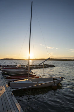 A classic 40ft sailboat gently moored by a rustic dock at sunset on Lake of the Ozarks.
