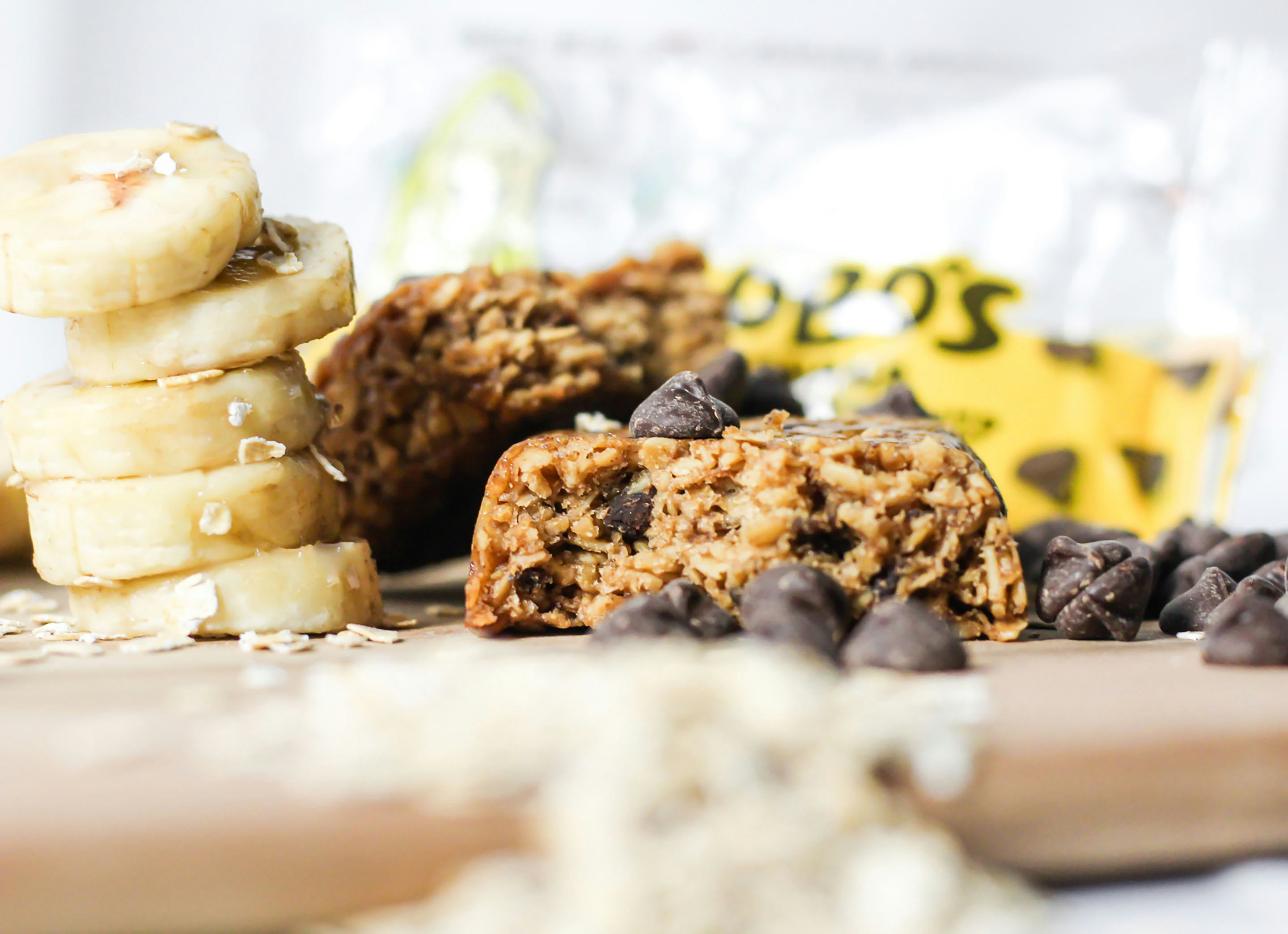 Oat granola bars with chocolate chips wrapped individually on wooden surface