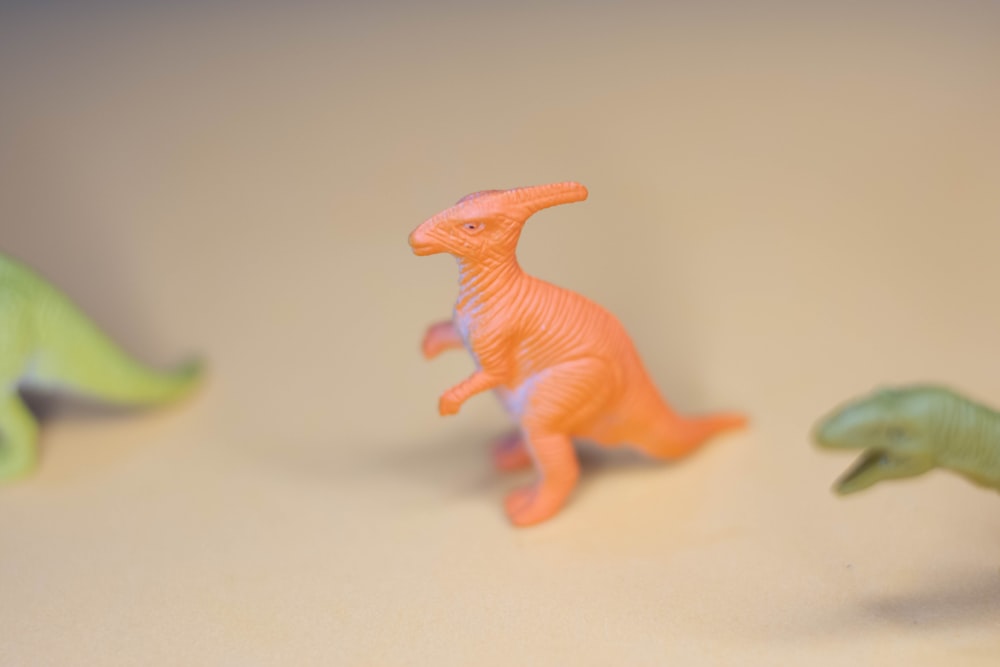 orange dinosaur plastic toy on white table