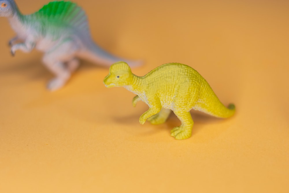 green dinosaur plastic toy on yellow surface