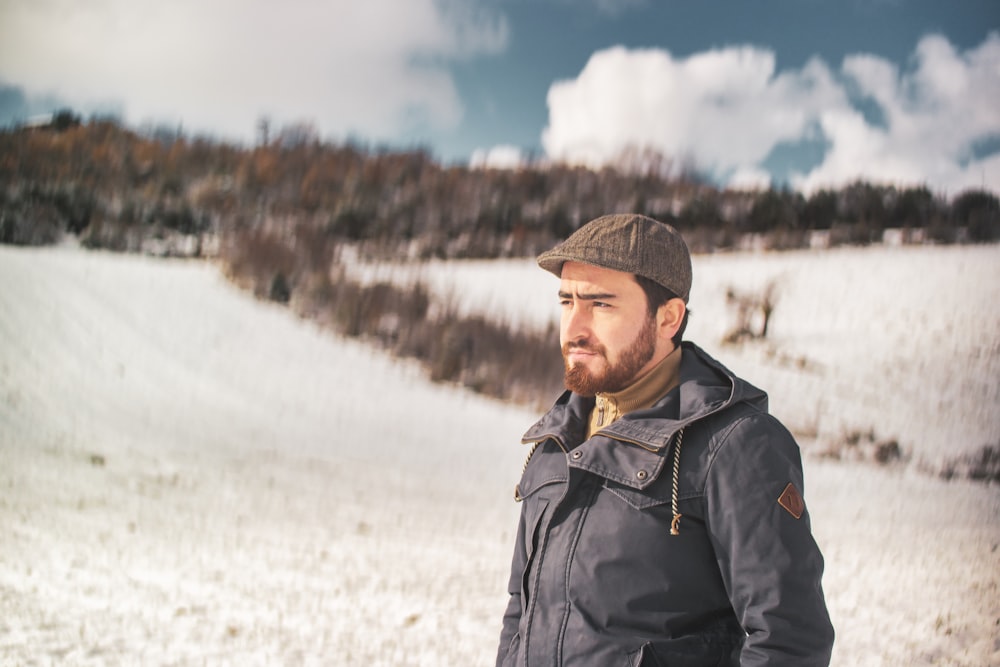 man in black jacket standing on snow covered ground during daytime