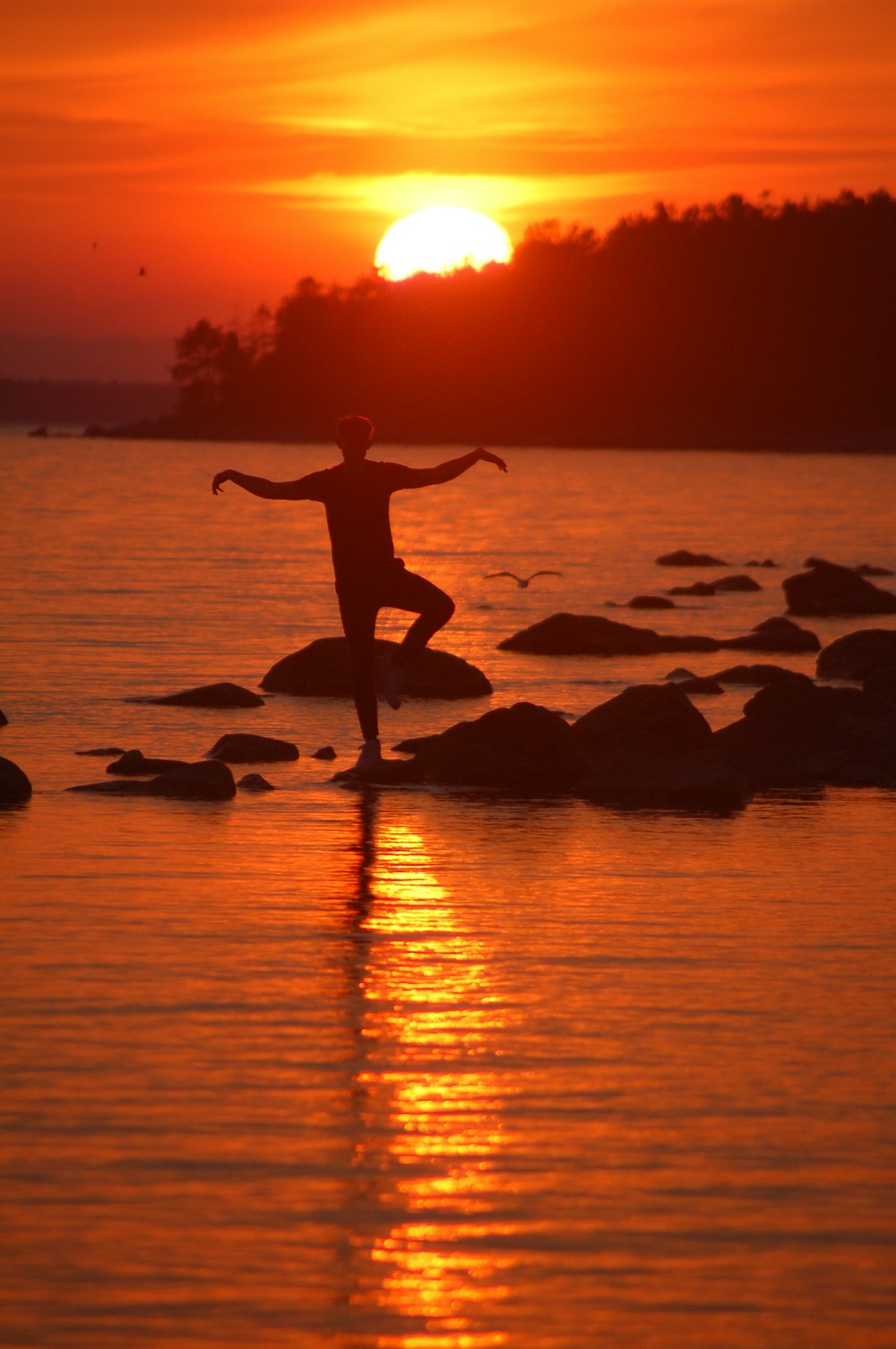 woman in black bikini jumping on water during sunset