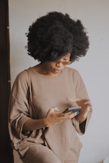woman in brown long sleeve shirt holding smartphone