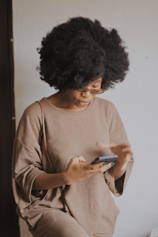 woman in brown long sleeve shirt holding smartphone