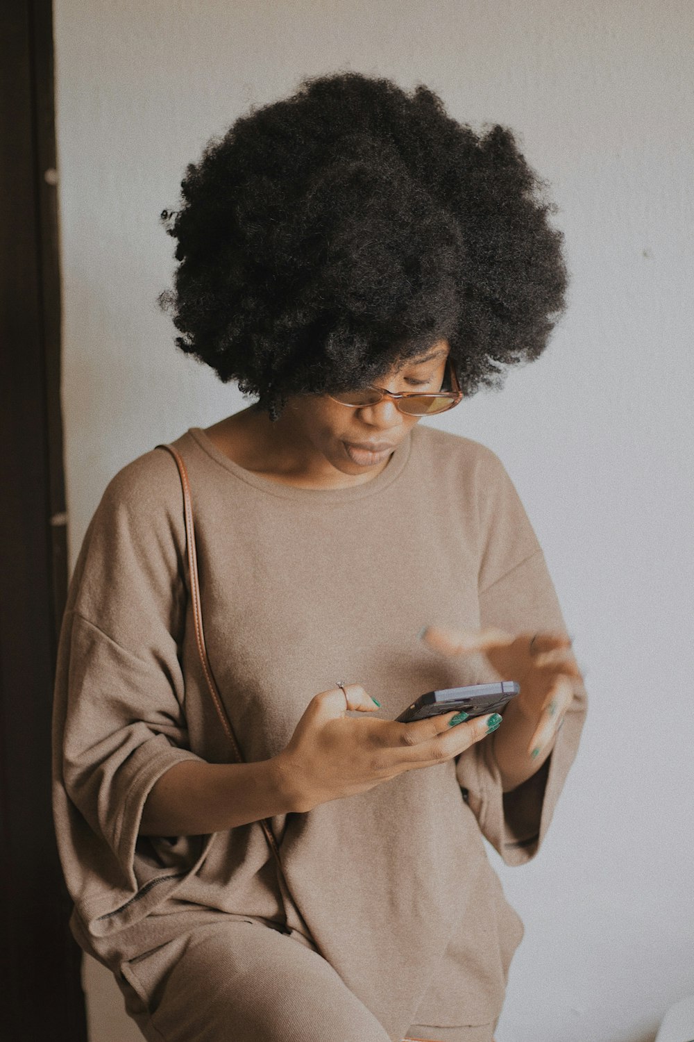 woman in brown long sleeve shirt holding smartphone