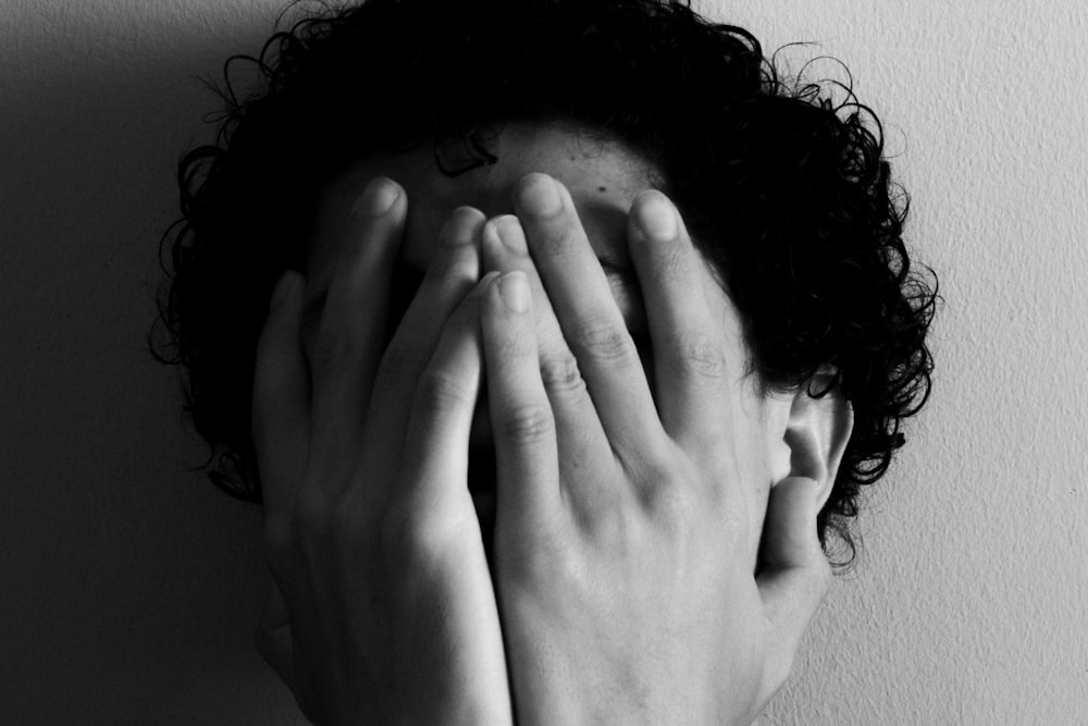 grayscale photo of woman covering her face