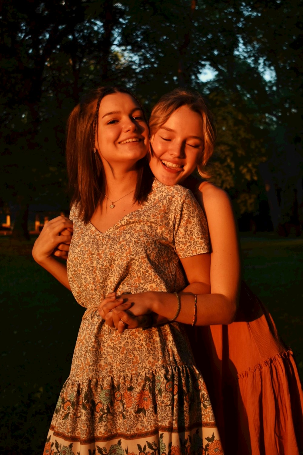 2 women smiling while standing on green grass field during daytime