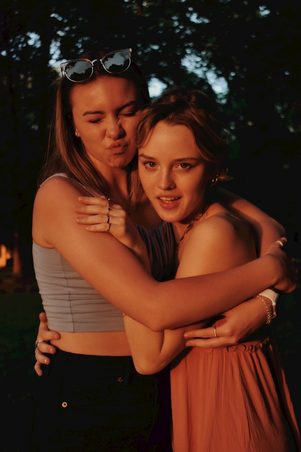 2 women smiling and standing near green trees during daytime