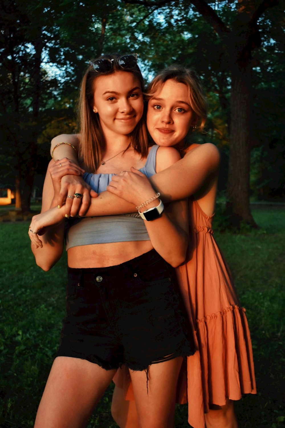 woman in orange dress hugging woman in black dress