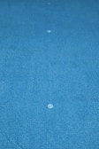 A view of a swimming pool floor covered in blue tiles with visible water drains placed in a symmetrical pattern.