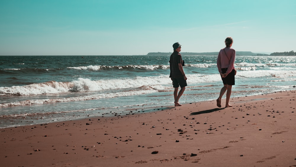 man and woman walking on beach during daytime