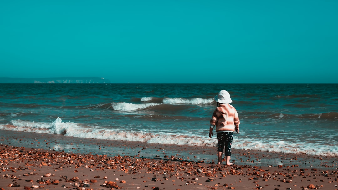 woman in white shirt and black shorts walking on beach during daytime