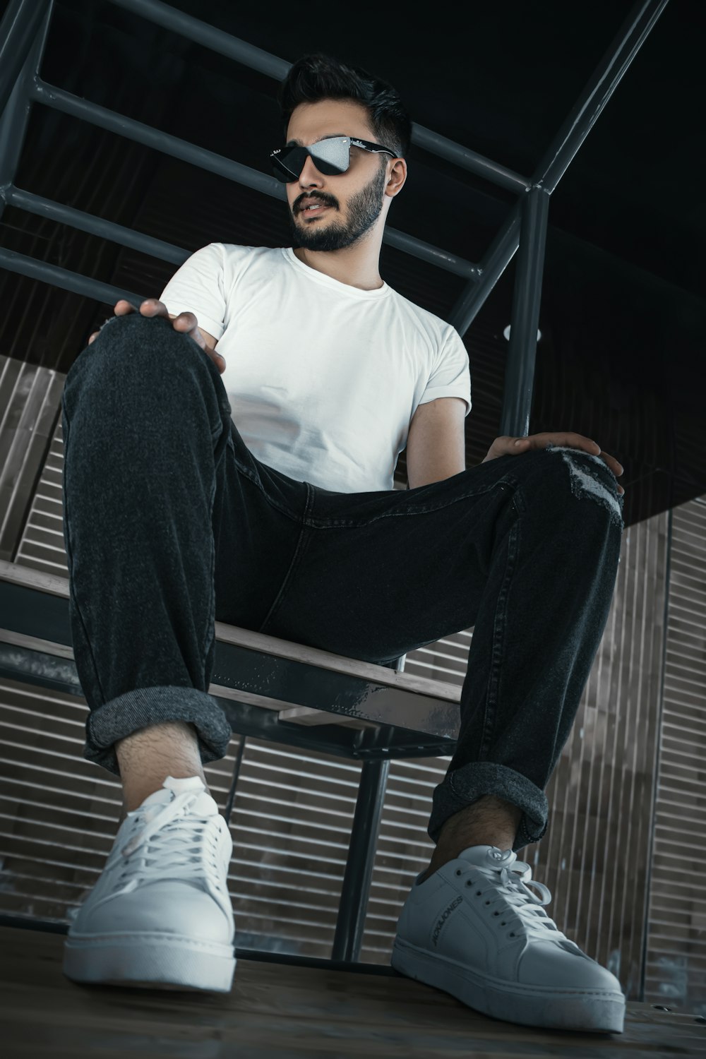 man in white crew neck t-shirt and black pants sitting on black metal bench