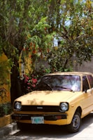 yellow car parked beside green tree during daytime