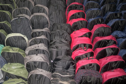 A collection of various backpacks displayed in an outdoor setting, showcasing different styles and colors.