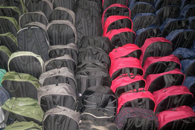 Rows of sturdy military backpacks in various sizes and colors displayed on wooden shelves.