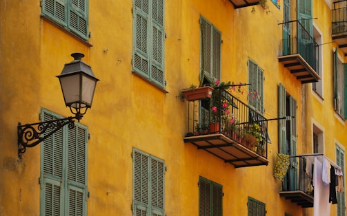 Exterior of a house with a vibrant yellow facade and contrasting dark green shutters.