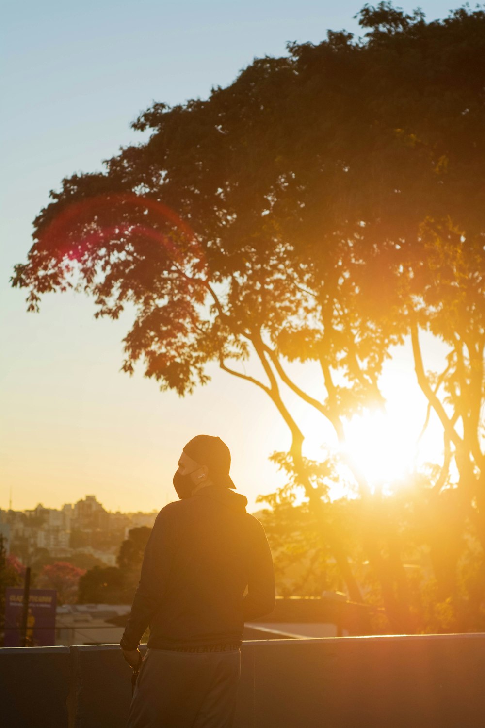 man in black jacket standing under tree during sunset