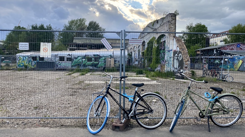 blue and black mountain bike parked beside gray metal fence during daytime