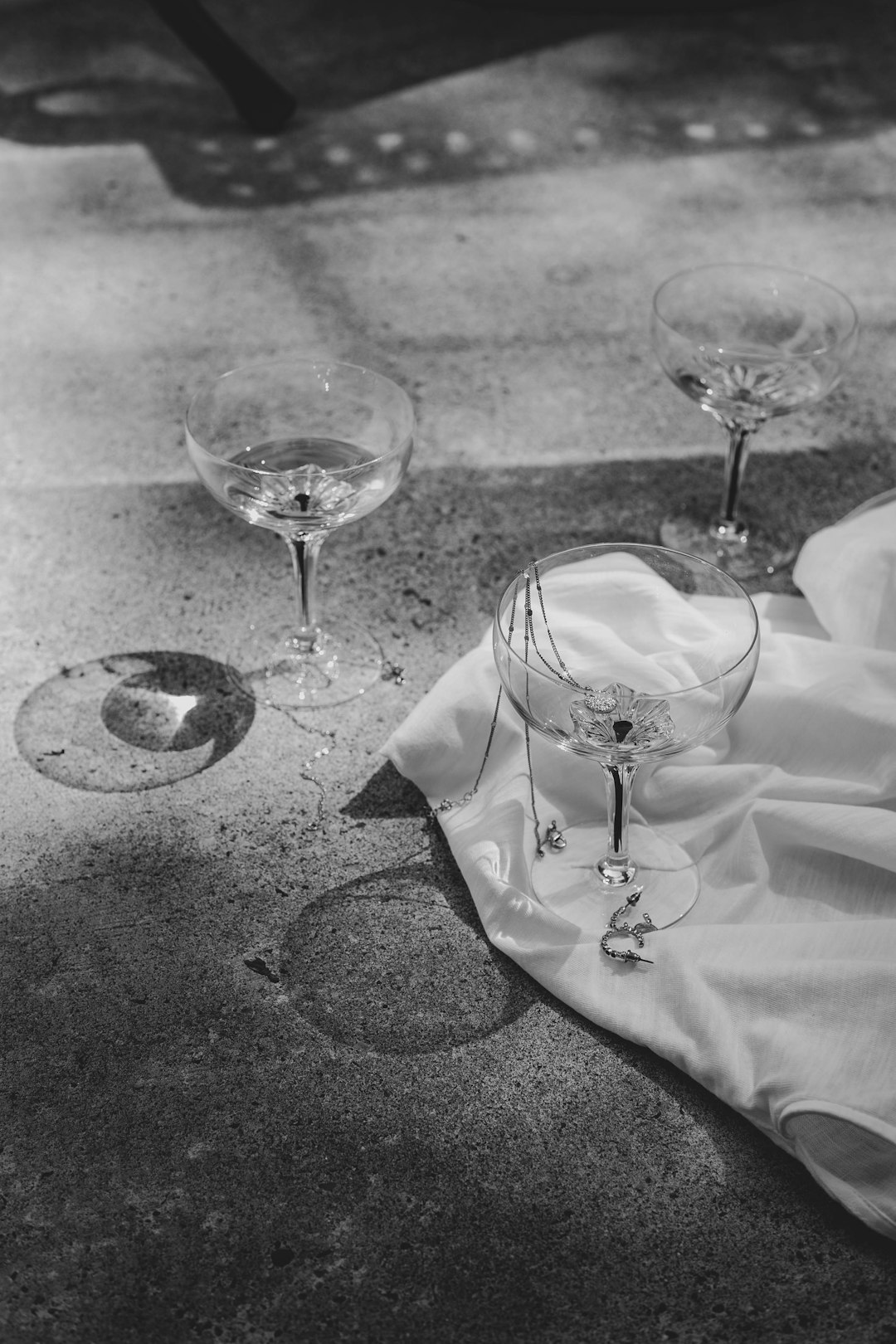 grayscale photo of wine glass and wine glass on table