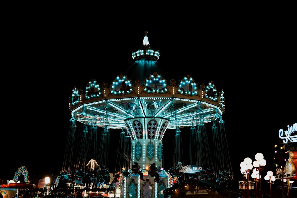 people standing near white and blue lighted carousel during night time