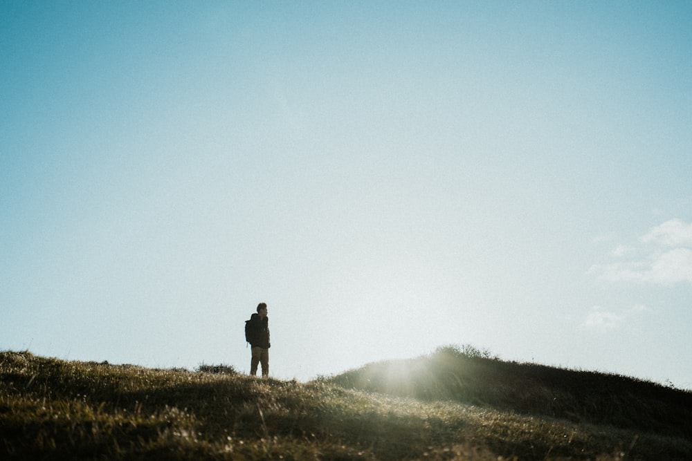 person in black jacket standing on green grass field during foggy weather