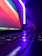 Close-up of a satisfied woman working on a laptop with purple neon lighting background.