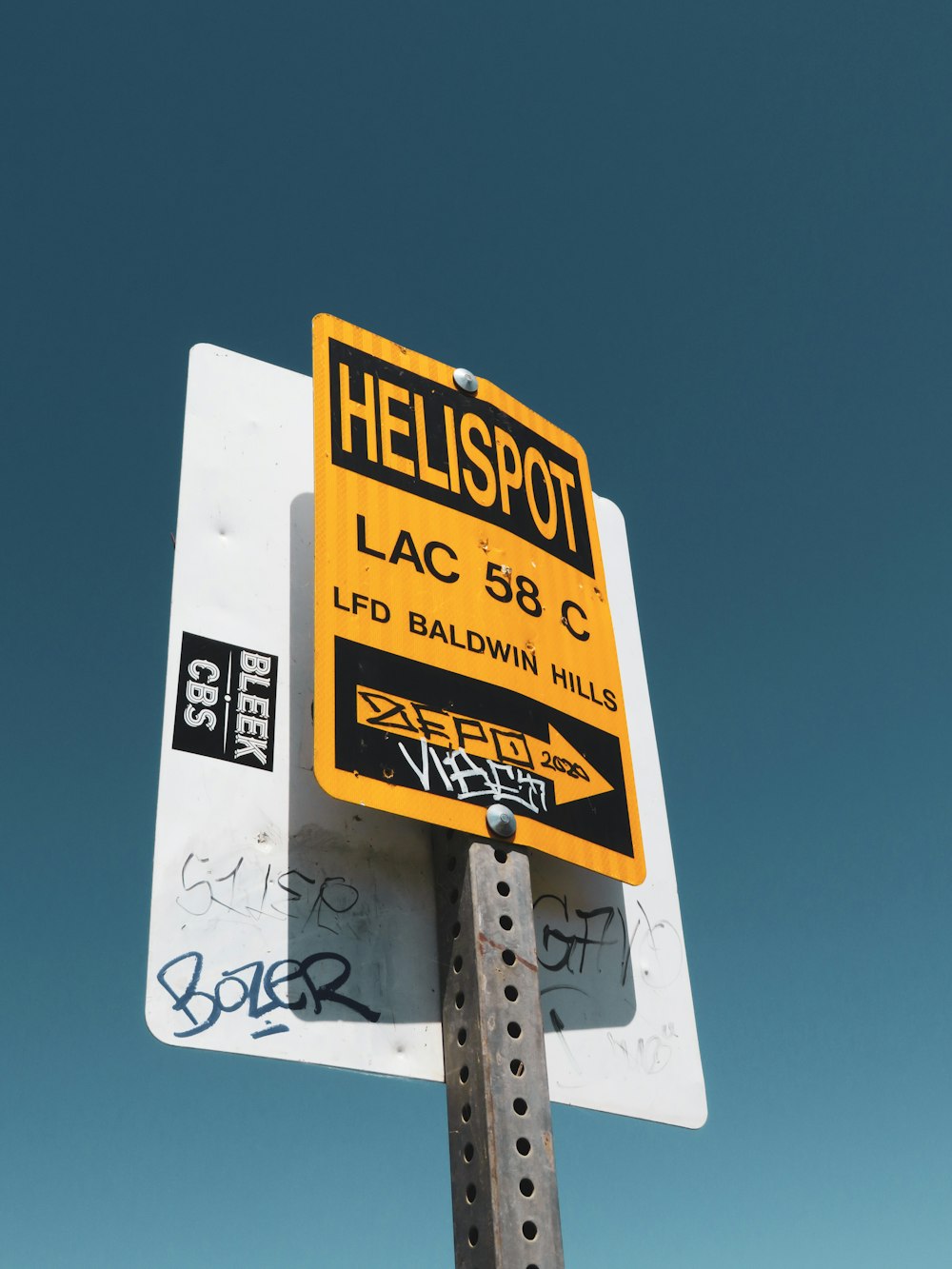 a yellow and black street sign sitting on top of a metal pole