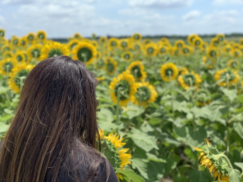 woman in black shirt standing in sunflower field during daytime