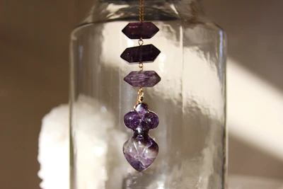 Close-up of a delicate violet amethyst pendant glowing softly in natural light.