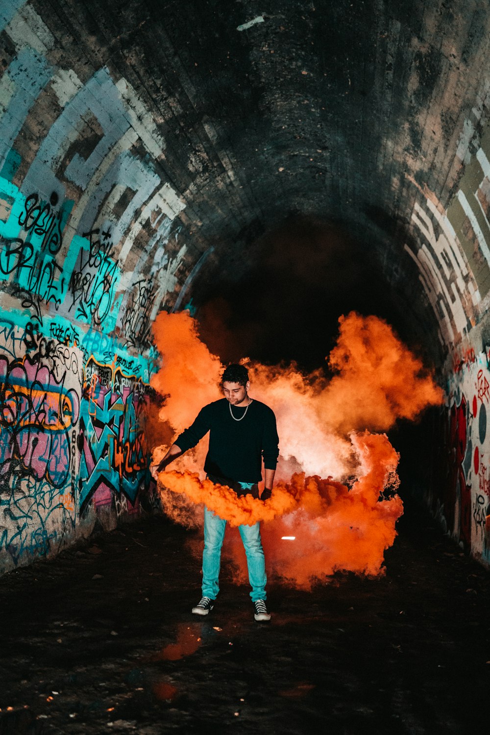 man in black long sleeve shirt and orange shorts standing in front of graffiti wall