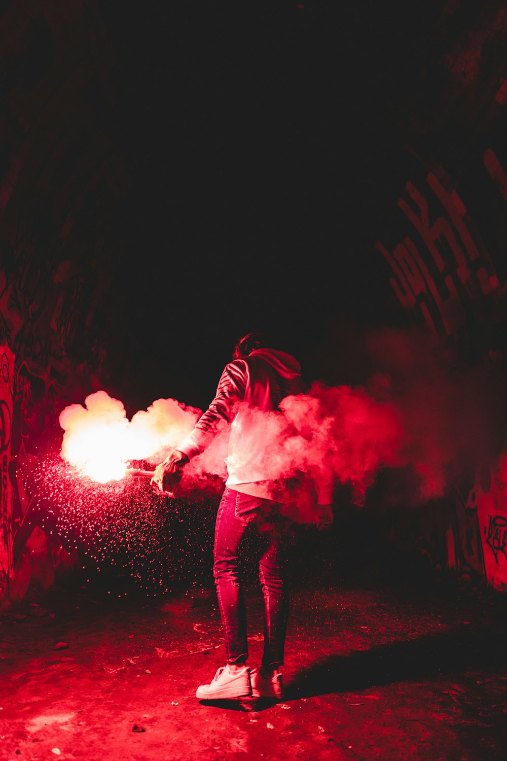 person in black and white striped hoodie standing on stage with red smoke