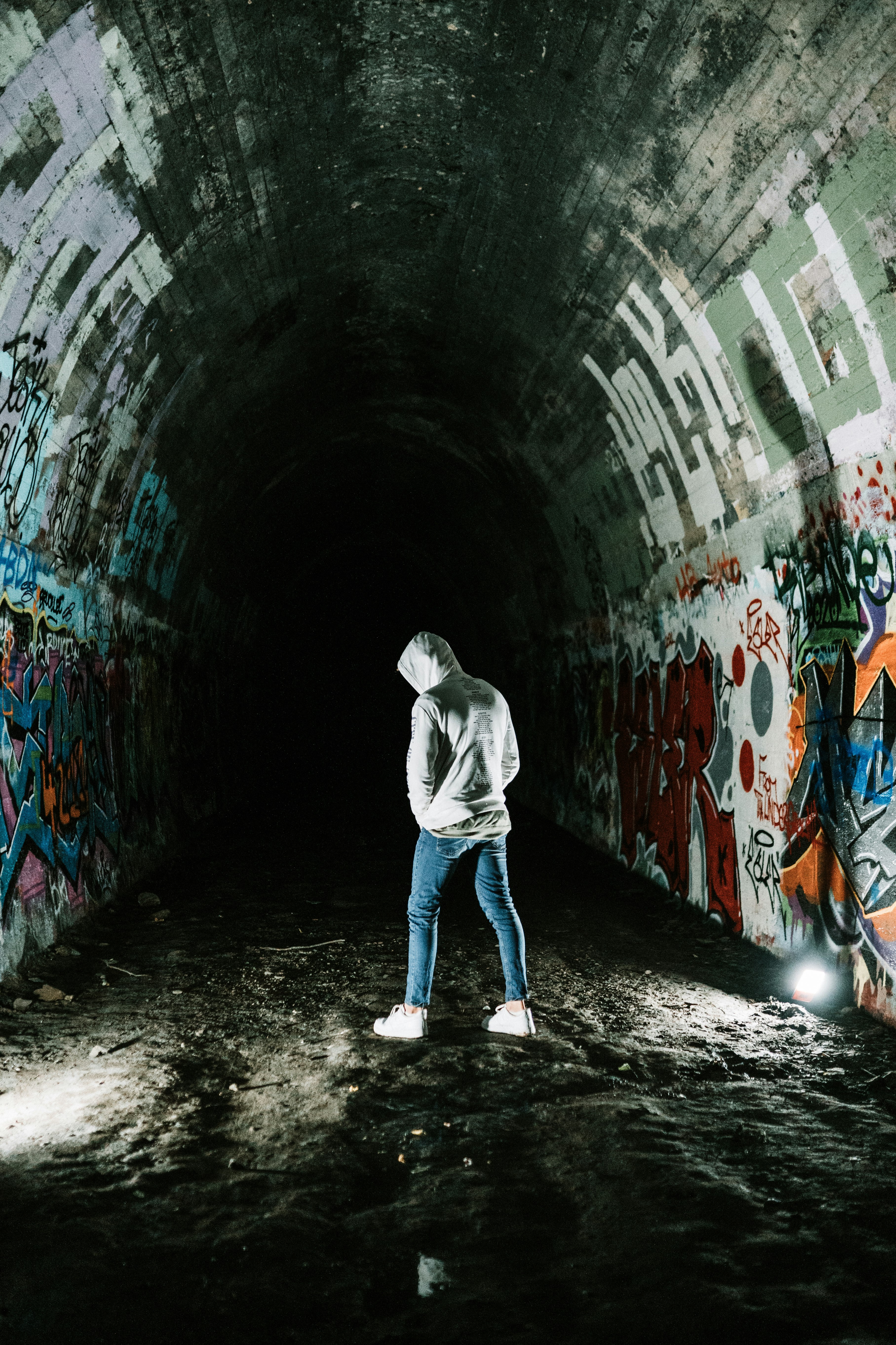 man in gray hoodie walking on tunnel