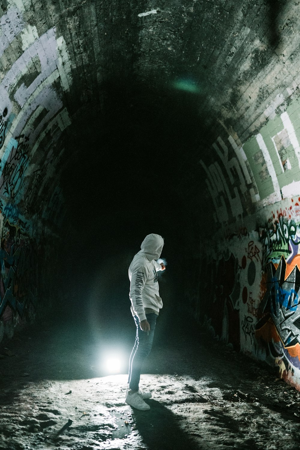 man in white hoodie walking on tunnel