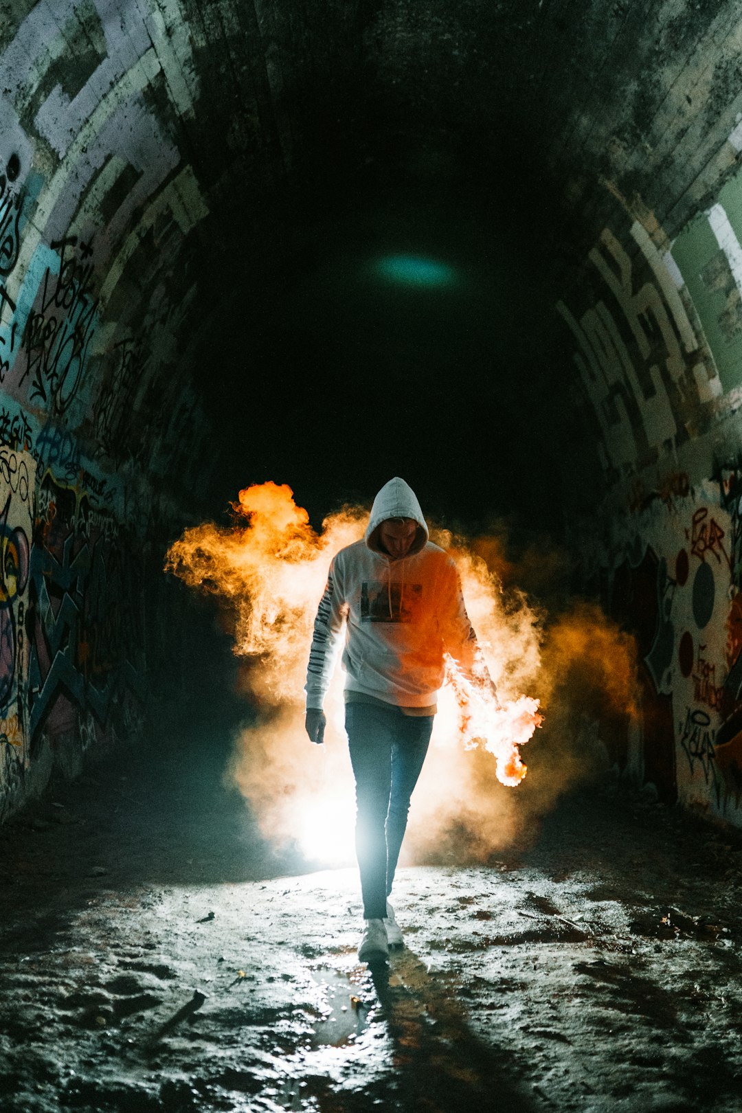 woman in orange jacket and blue denim jeans standing on tunnel