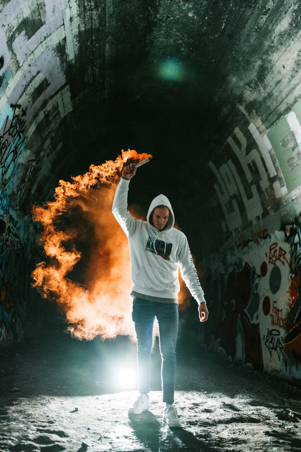 man in white long sleeve shirt and blue denim jeans standing on black and white tunnel