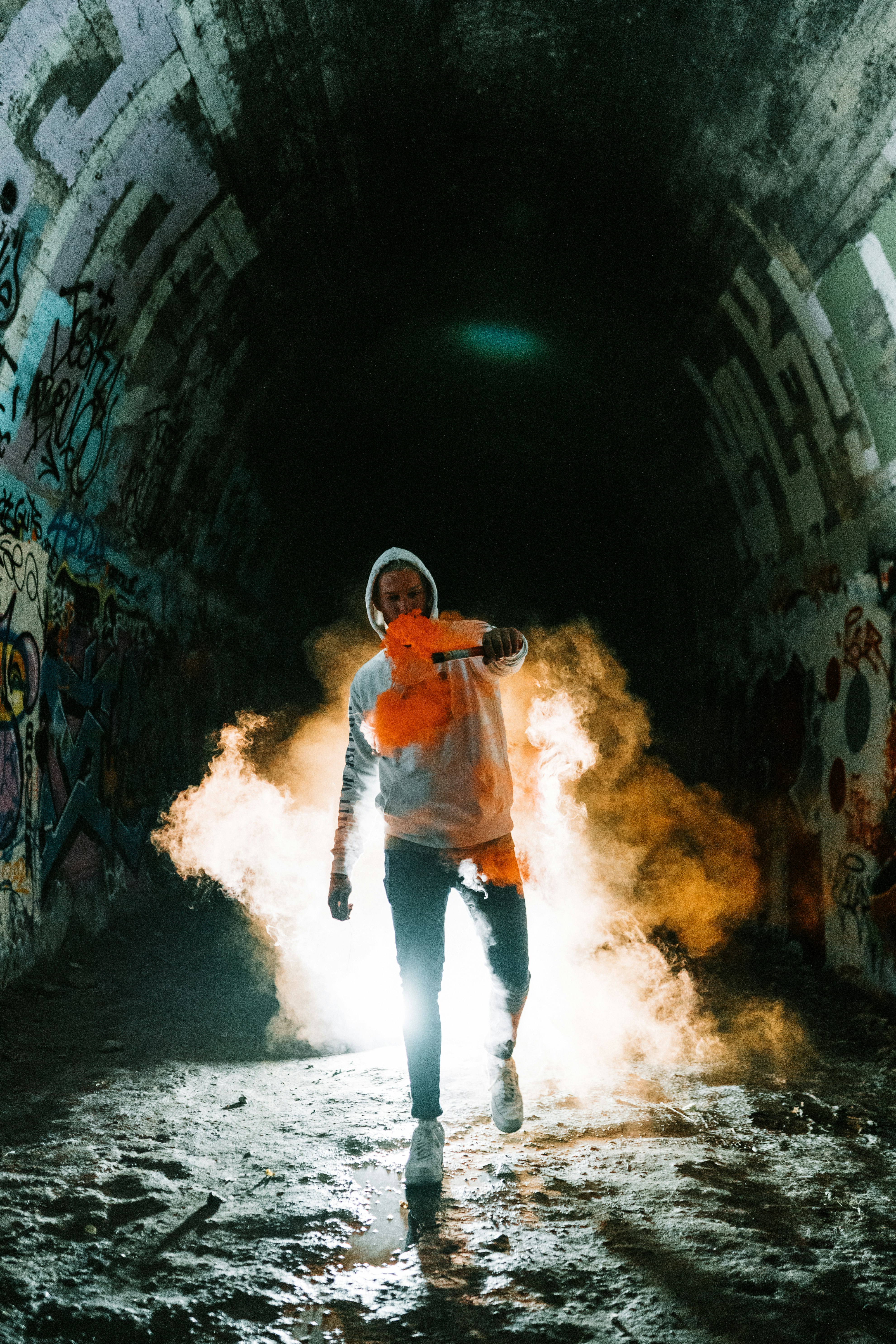 man in orange jacket and blue denim jeans standing on tunnel