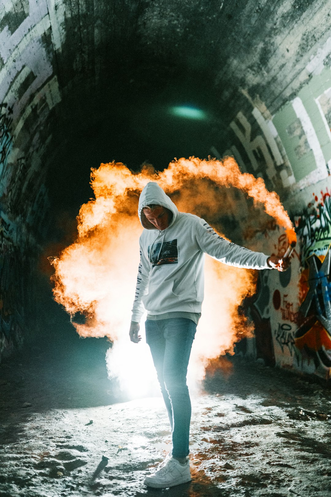 woman in gray hoodie and blue denim jeans standing on black and brown tunnel