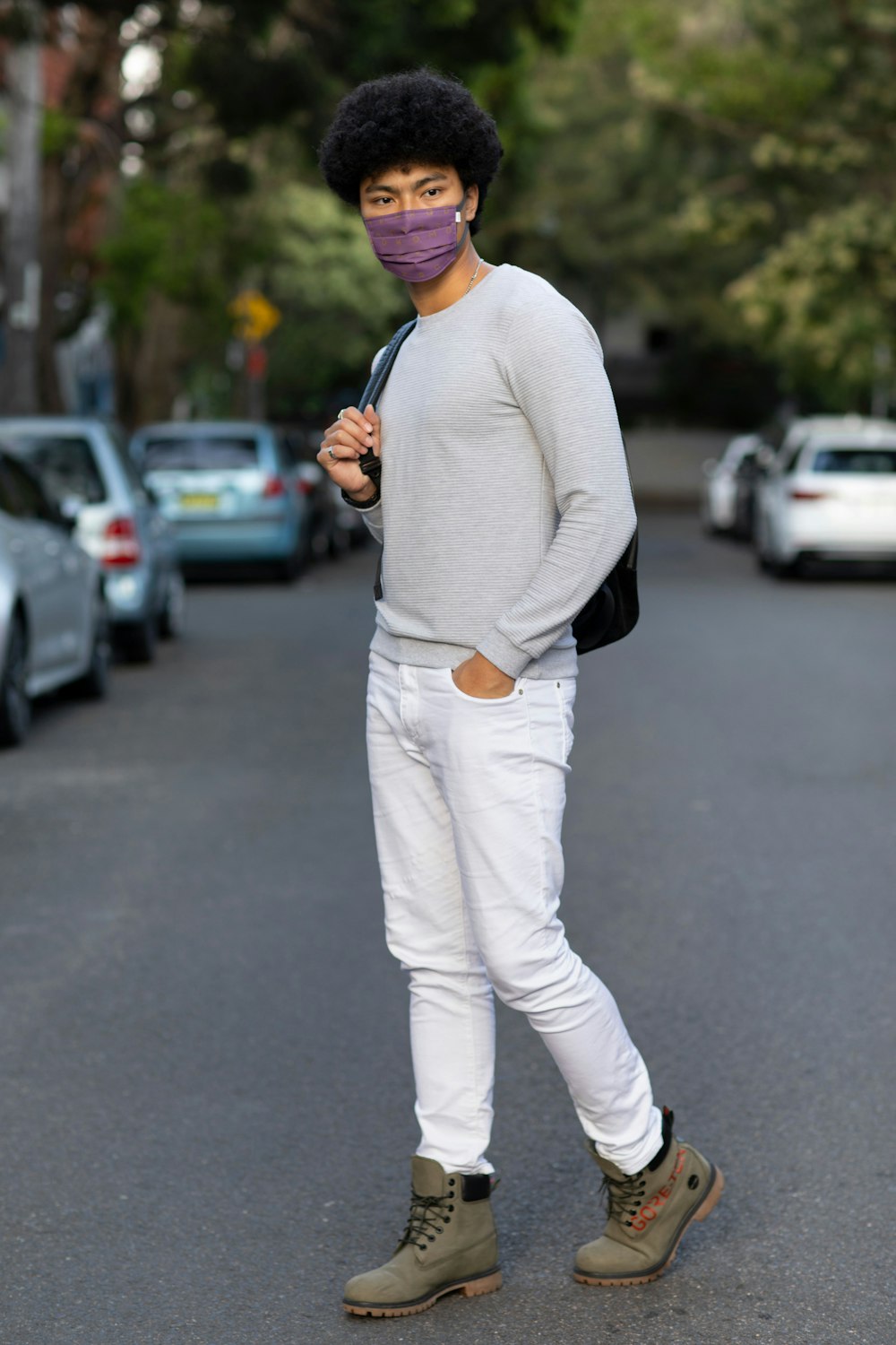 man in white sweater and pants standing on road during daytime