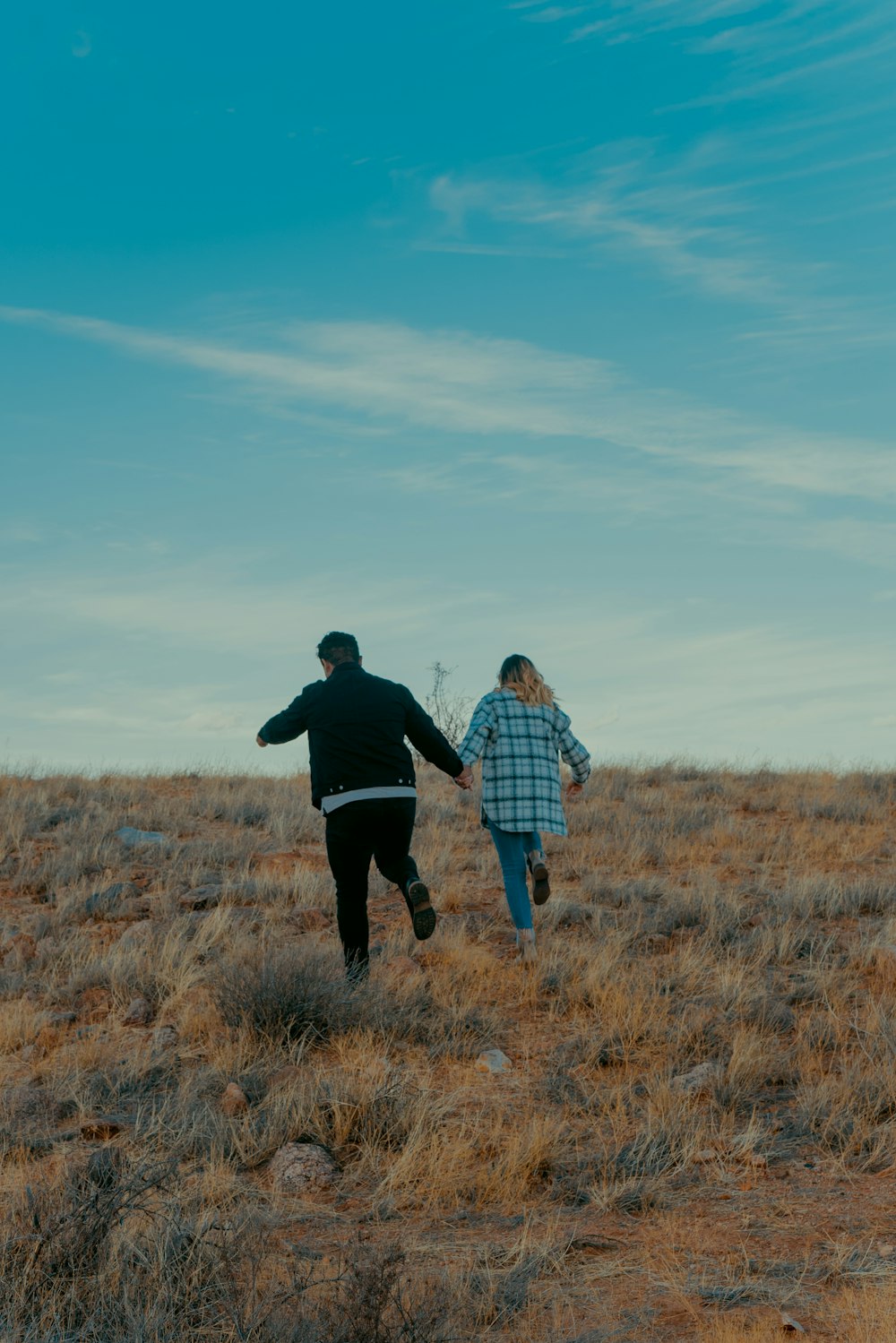 man and woman standing on brown grass field during daytime