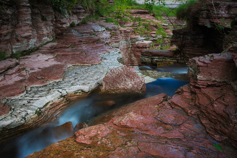 brown rocky river in between of rocky mountains during daytime