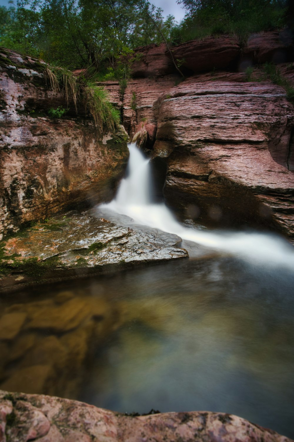 water falls between brown rock formation during daytime