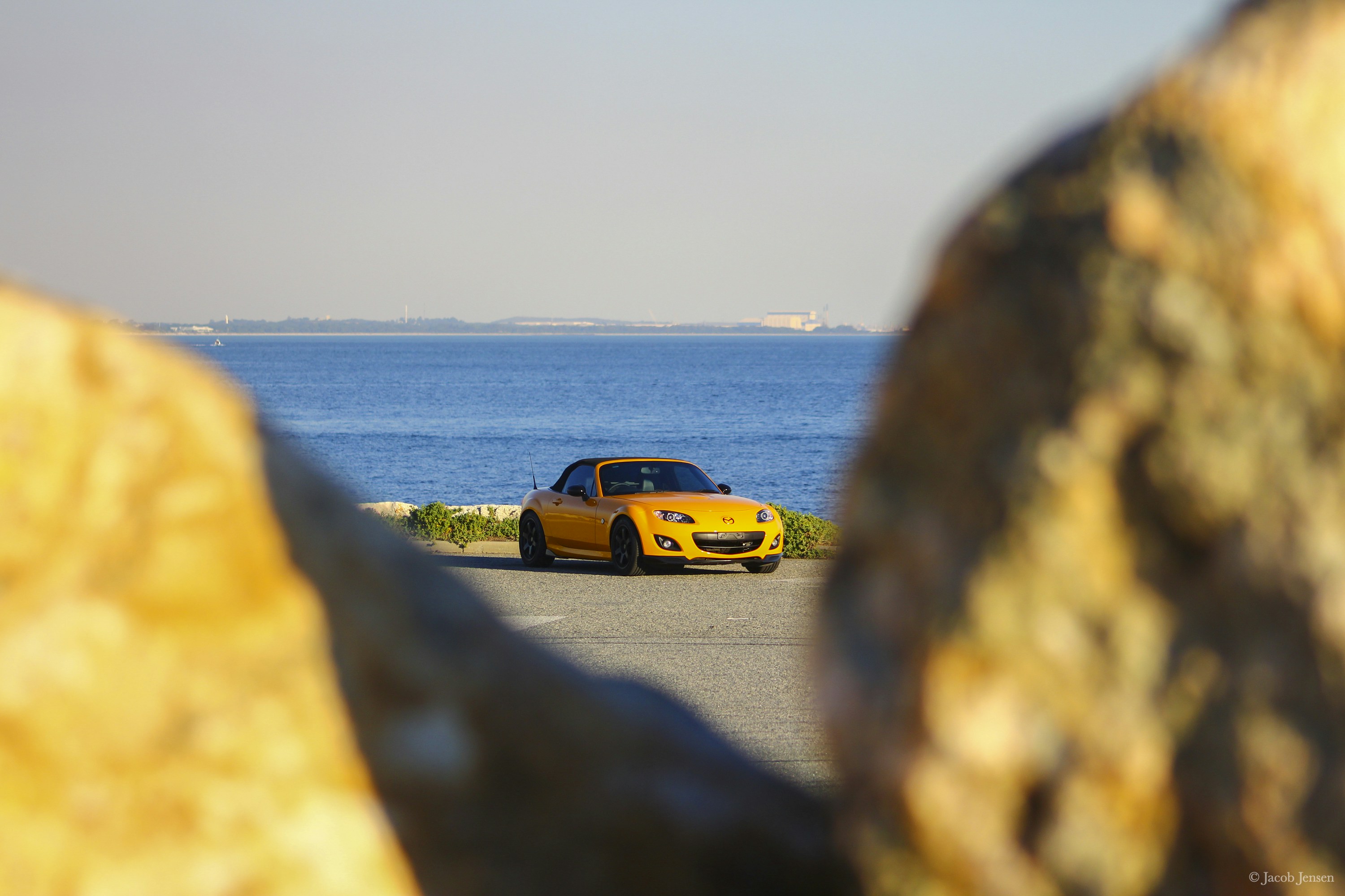 yellow car on road near body of water during daytime