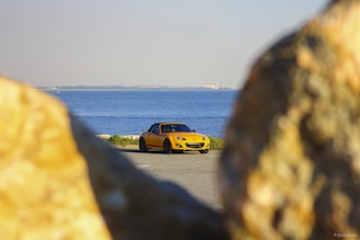 yellow car on road near body of water during daytime