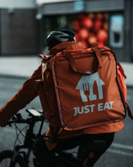 person in black jacket and orange and black backpack walking on sidewalk during daytime