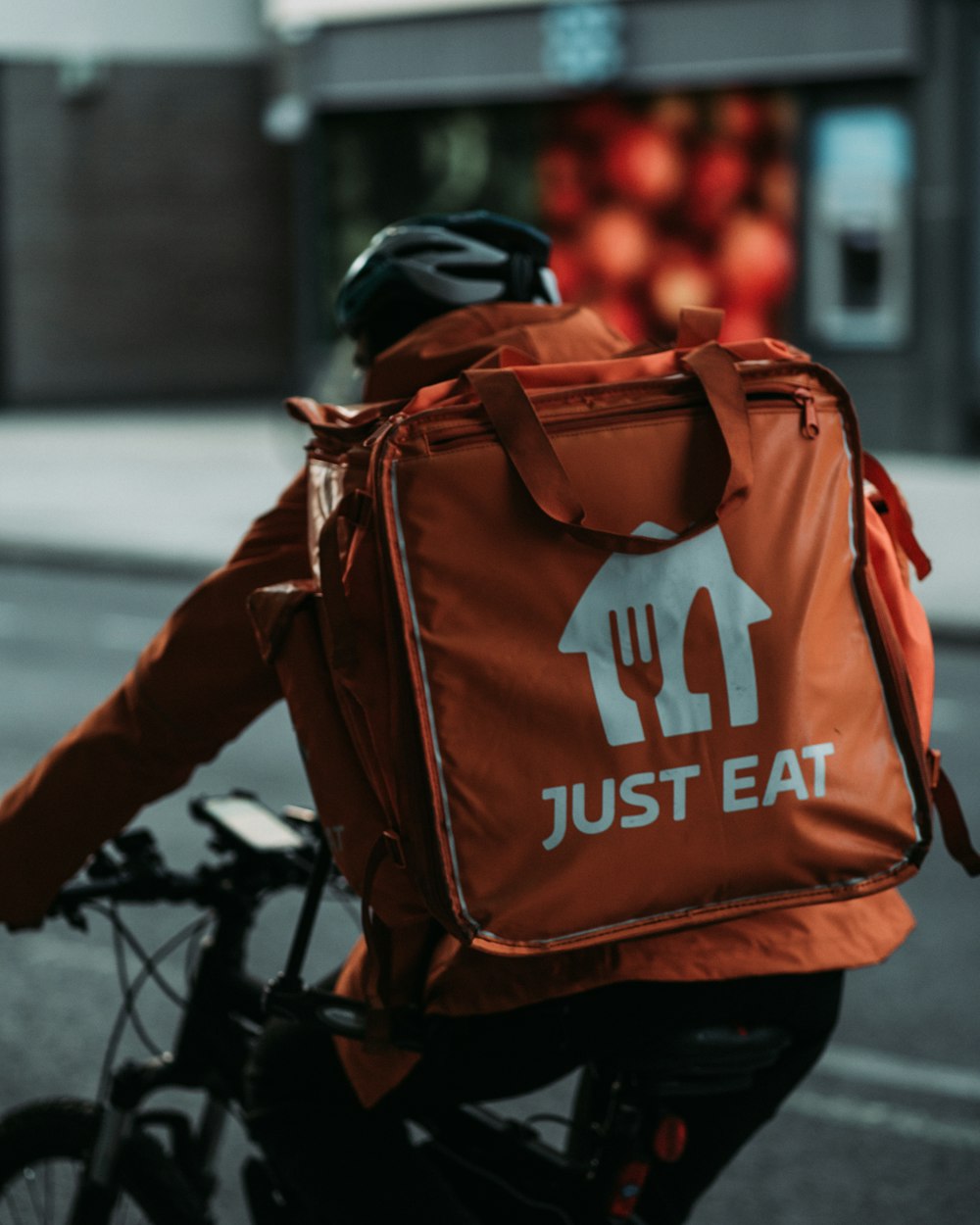 person in black jacket and orange and black backpack walking on sidewalk during daytime