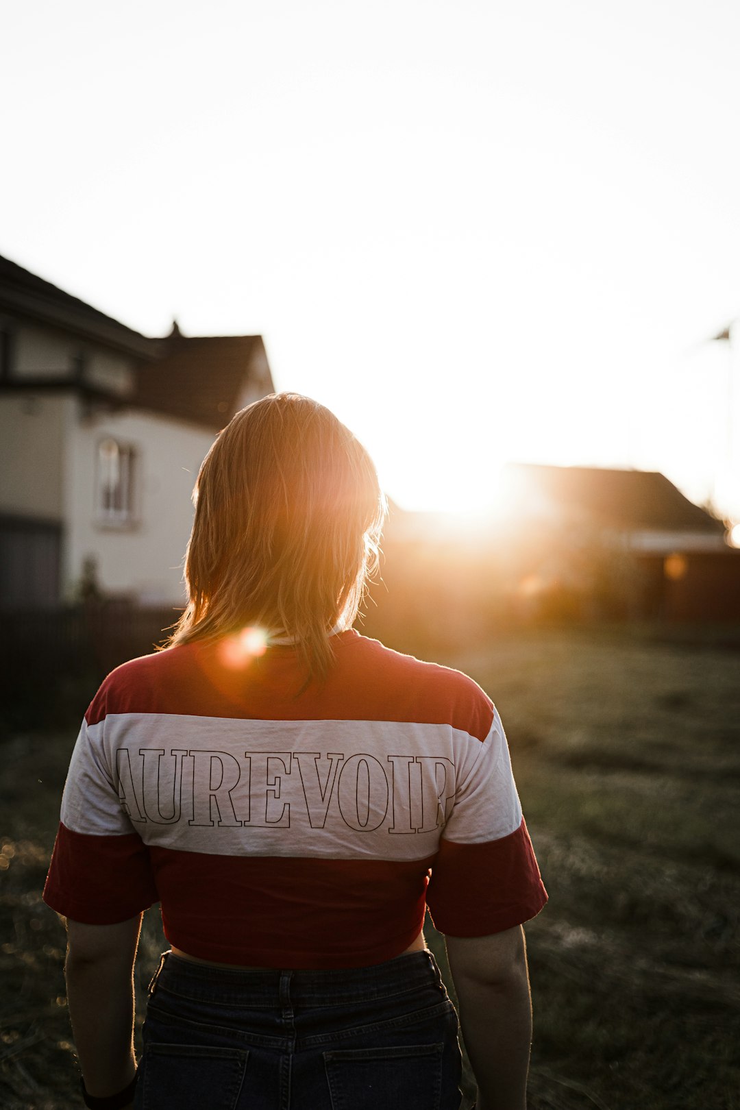 woman in white and black striped shirt standing on road during sunset